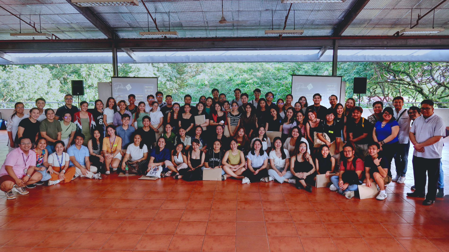 A group of roughly 100 people huddle together for a group photo.