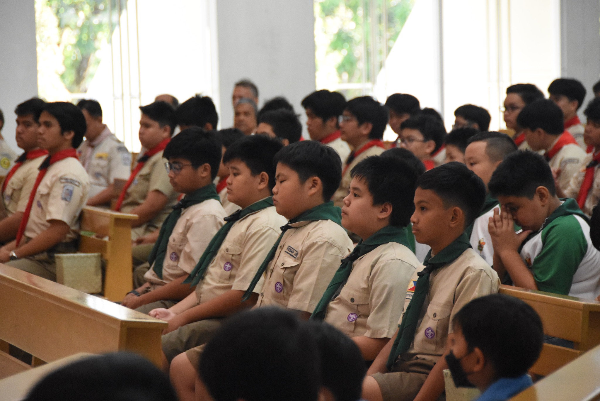 Distinguished by their green neckerchiefs, the Boy Scouts listen to the homily during the Thanksgiving Mass