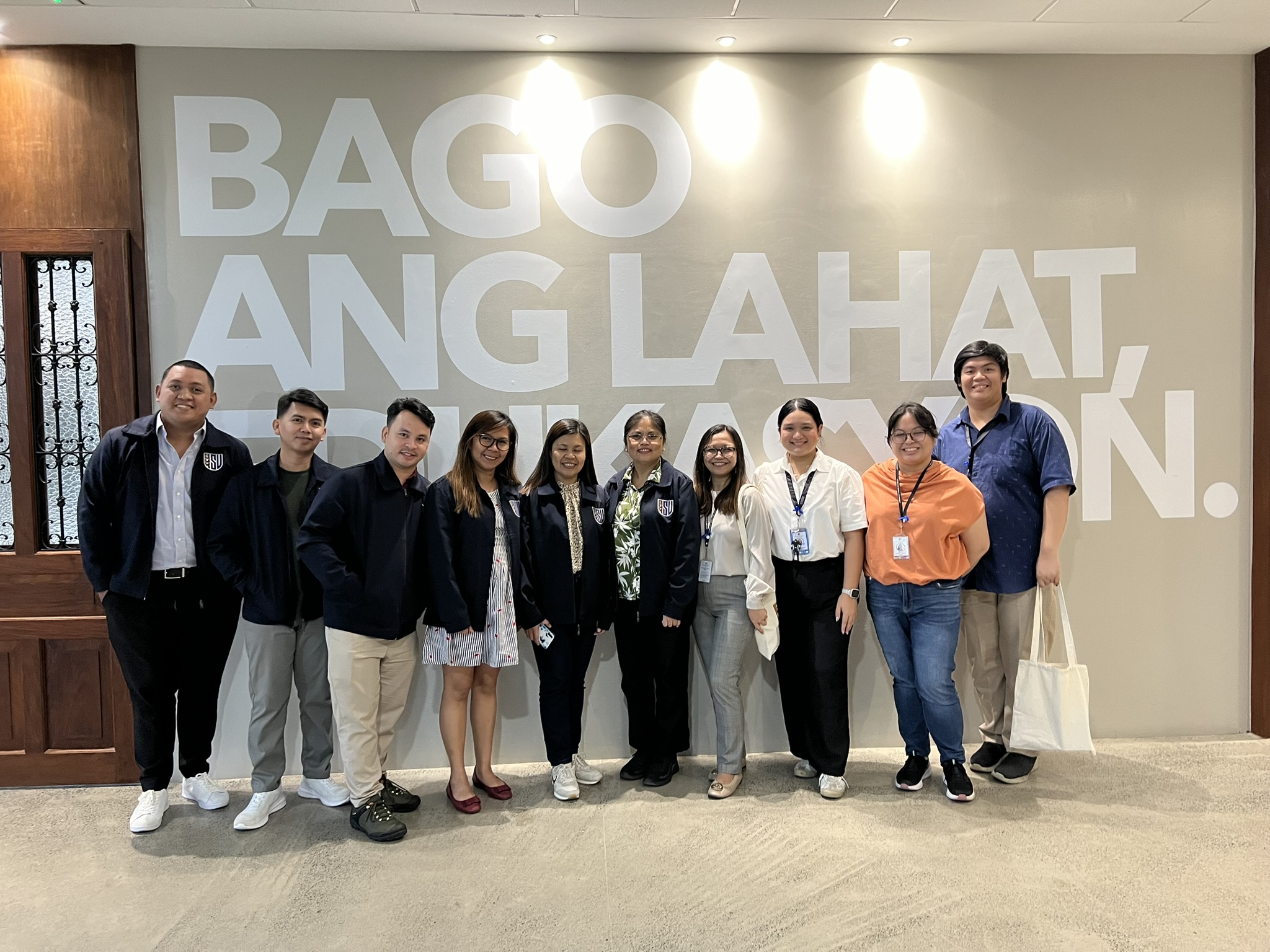 Members of Bukidnon State University Academic Mentoring Unit and Pathways to Higher Education stand in a line in front of a mural that says "Bago ang Lahat, Edukasyon."