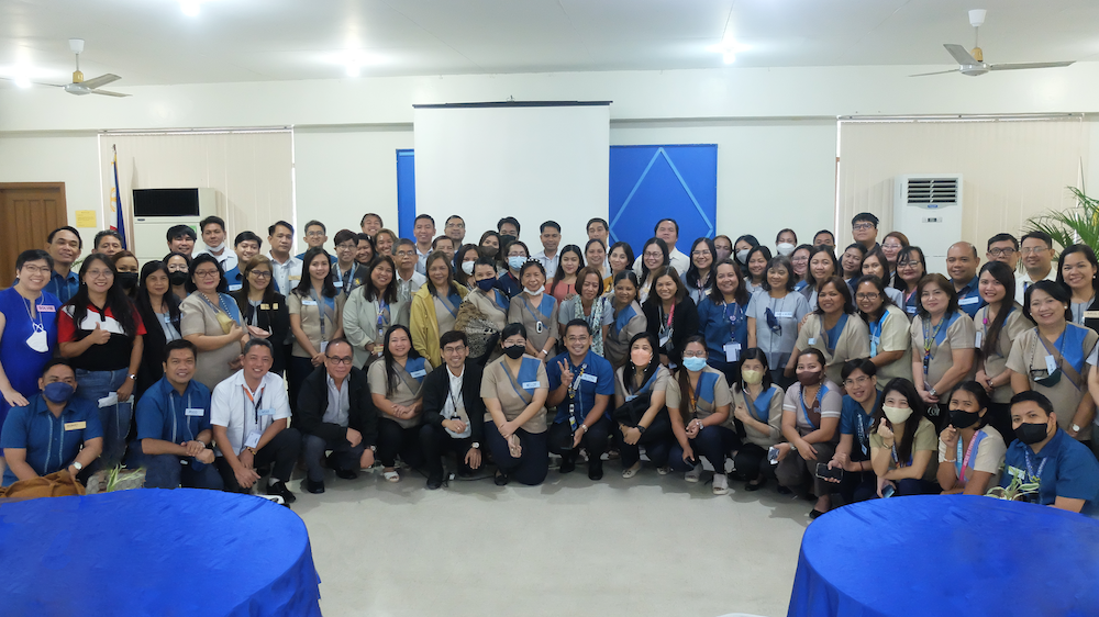 Teachers, principals, representatives from School District Offices of Marikina and Quezon City, and representatives from San Mateo, Rizal stand in three lines for a group photo. They are all in their respective uniforms for the day.