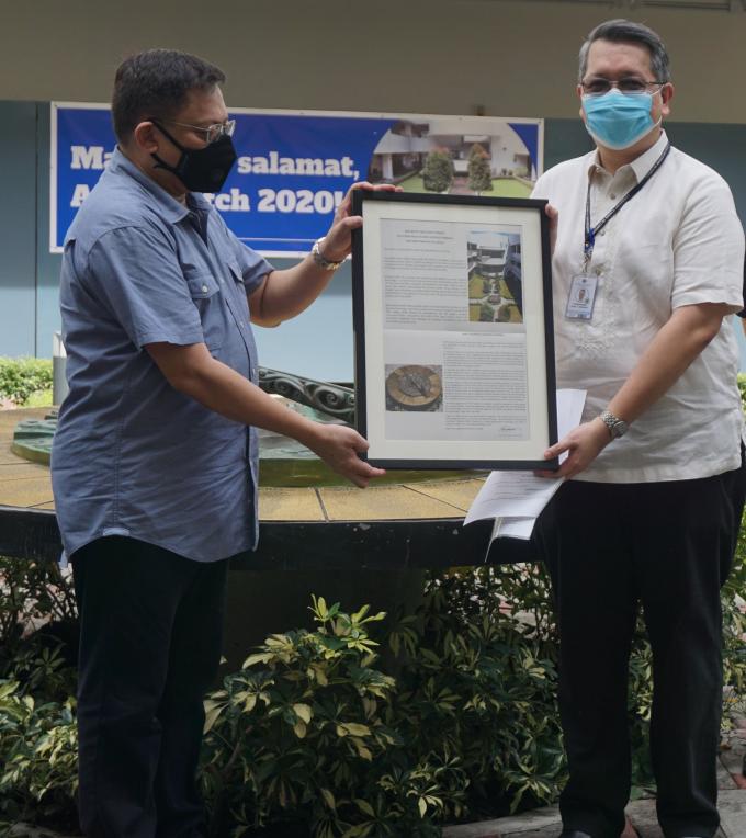 Rene Santos (left) hands the plaque to Noel Miranda
