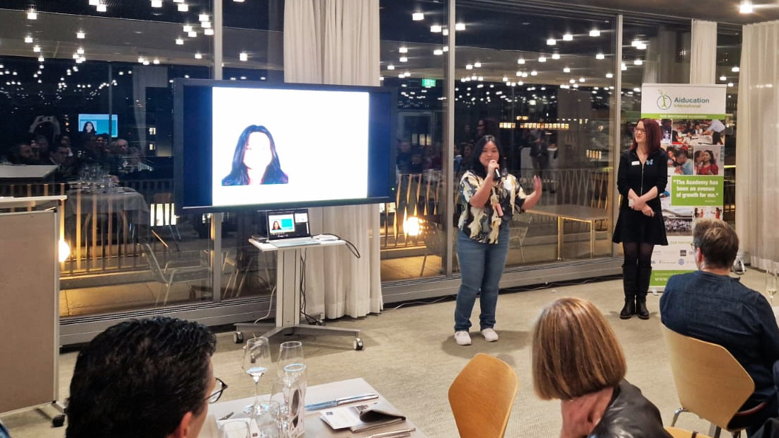 Magcalas, a shorter Filipino young adult, speaking to a seated European audience.