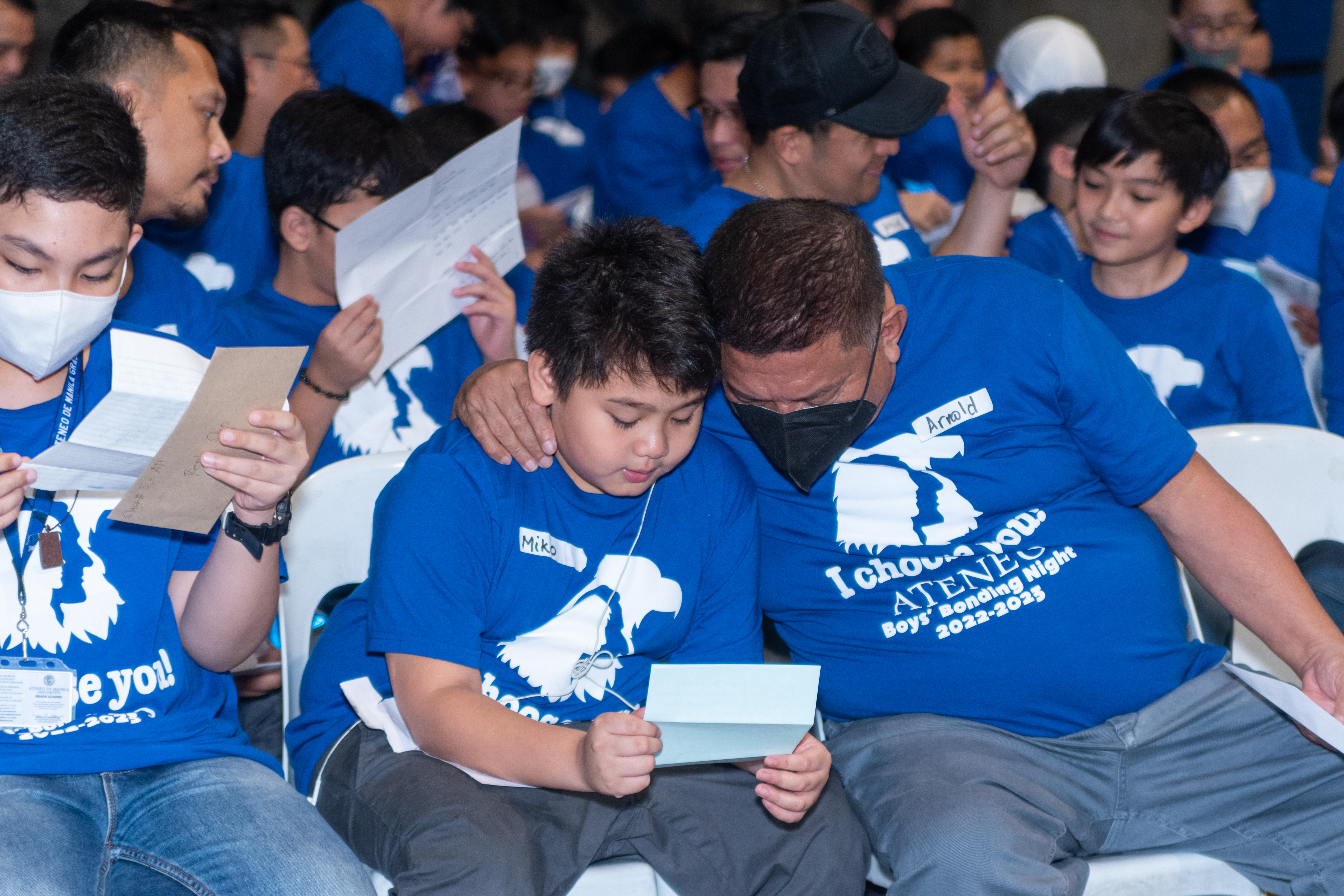 A touching scene - a father with his arm around his son’s shoulder as the boy reads dad’s letter