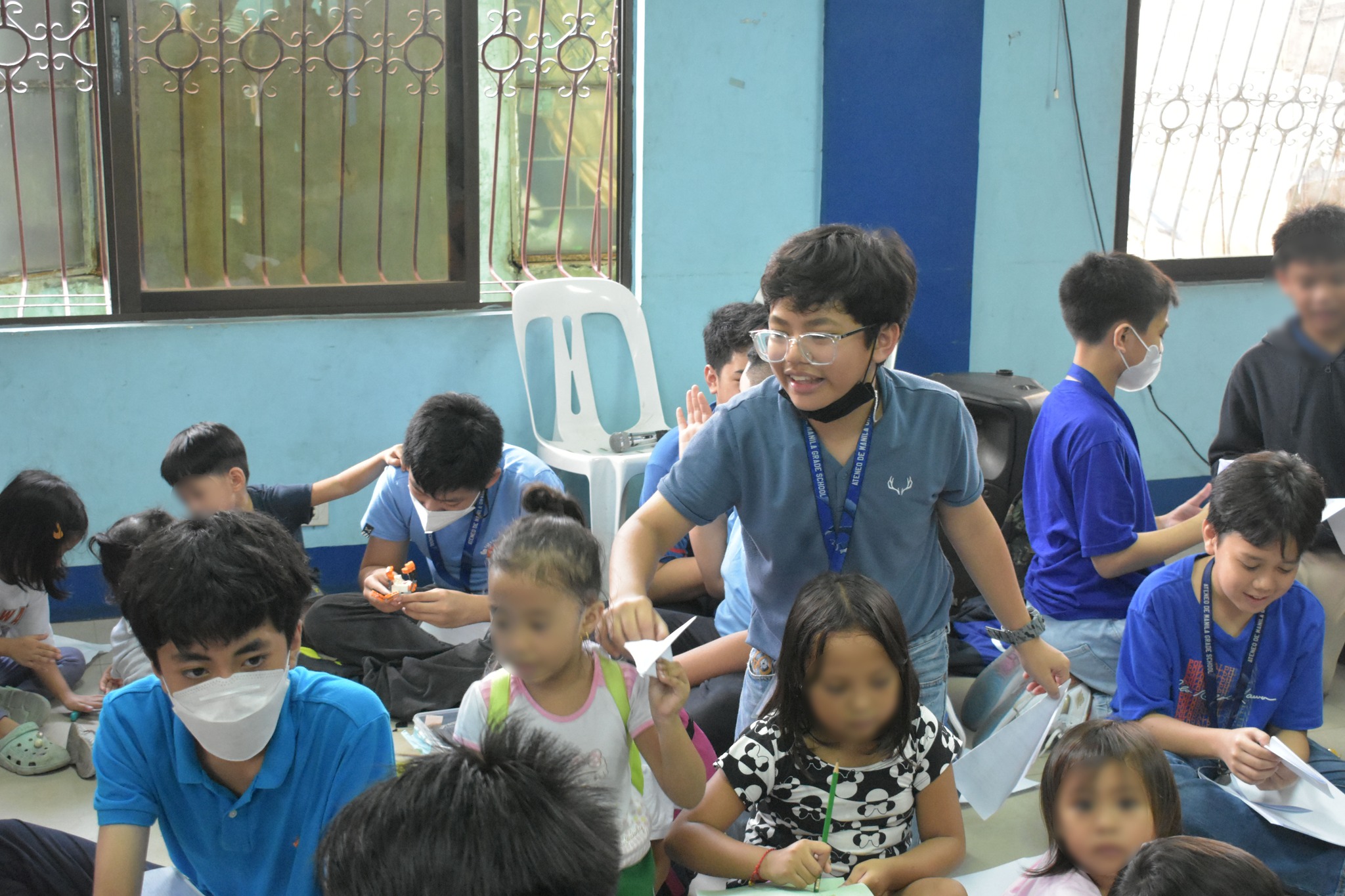A boy from 7-Andlauer hands a paper plane he made to a child from the Barangay Escopa 3 Day Care Center