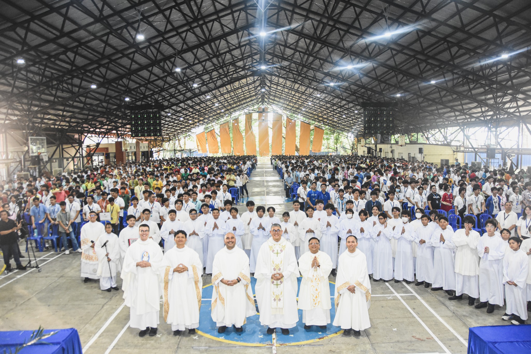 From left: Fr Michael Rossman, SJ (USA), Fr Thep Sarayuth, SJ (Thailand), Fr Edryan Paul J Colmenares SJ, Fr Xavier L Olin, SJ (Provincial Superior, Society of Jesus in the Philippines), Rev Deacon Rico J Adapon SJ, and Fr Mamert B Mañus SJ gather for a commemorative group shot with the Junior High School community behind them at the close of Easter Mass