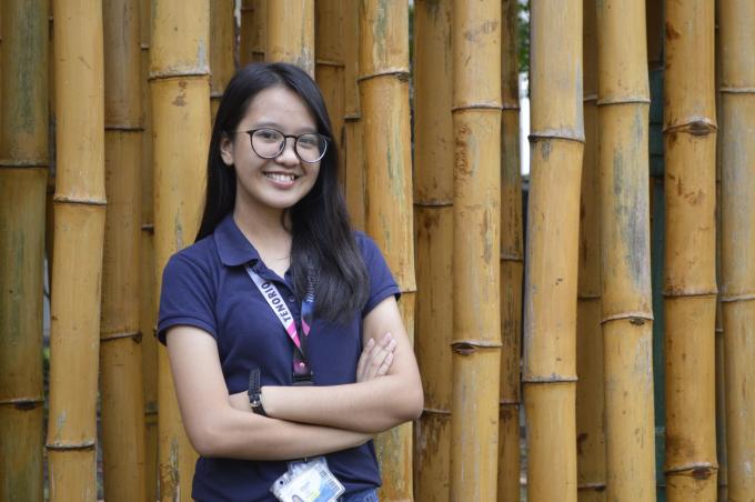 A young student poses with her arms crossed and a smile on her face.