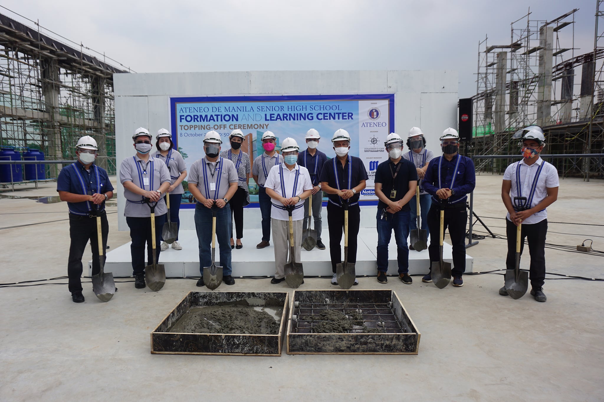 University President Fr Roberto C Yap SJ (center, in white shirt) and other university officials and administrators pose for a photo before the start of the ceremonial topping-off
