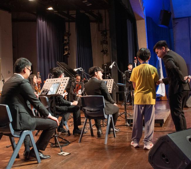 A Grade 5 boy tries his hand at conducting an orchestra 