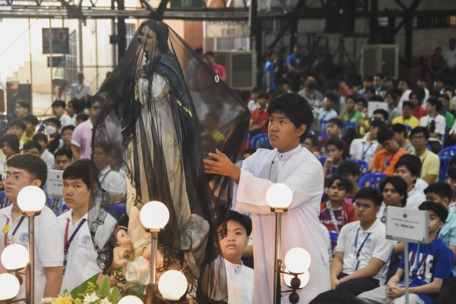 An altar server unveils the image of the Blessed Virgin Mary during the 'Salubong' of AJHS' Lux in Domino Mass  